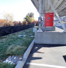 A swale separates the parking area, roofed in solar panels, from inland canals.