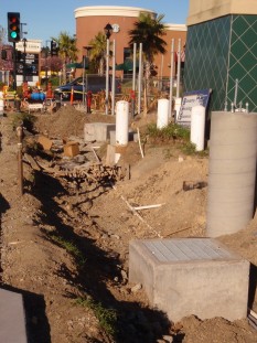 Swale under construction, Abella shopping area New construction with drain box and irrigation pipes in ditch excavated for swale.